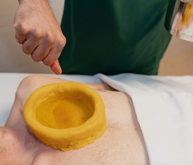 Therapeut führt Dauerölanwendung mit Teigring (kati-basti) auf dem Brustkorb des Patienten durch