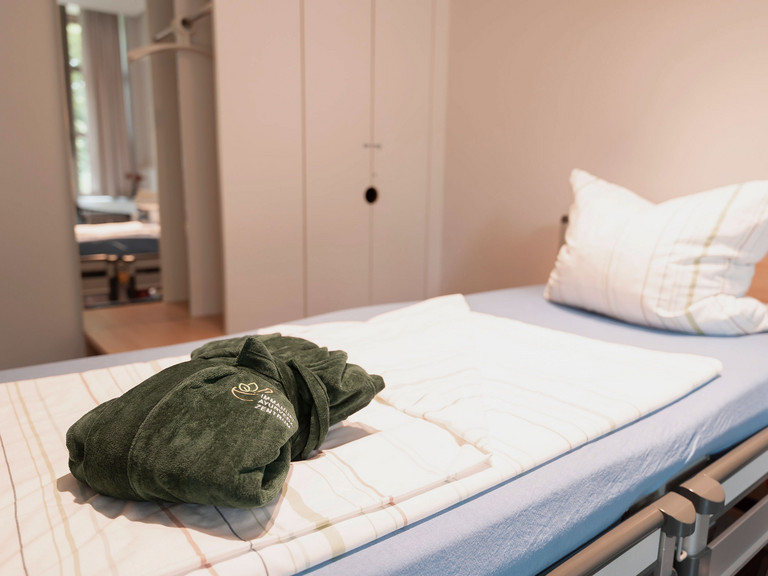 Patientenbett mit Bademantel im Immanuel Ayurveda Zentrum