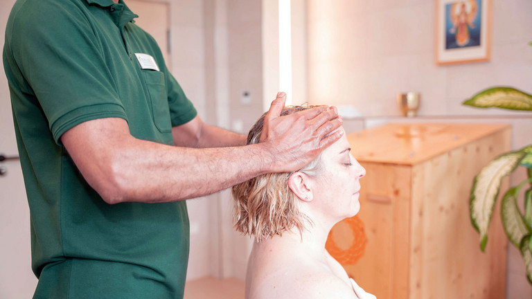 Therapeut massiert den Kopf der Patientin mit Öl - Immanuel Ayurveda Zentrum