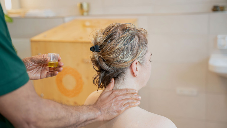 Therapeut trägt Öl für Nackenmassage bei Patientin auf - Immanuel Ayurveda Zentrum