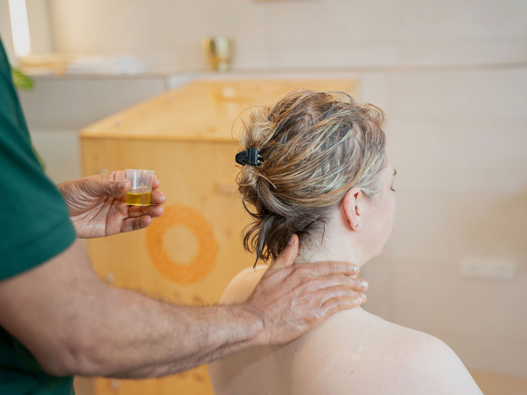 Therapeut trägt Öl für Nackenmassage bei Patientin auf - Immanuel Ayurveda Zentrum
