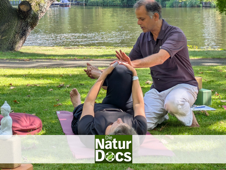 Yogatherapeut leitet Patientin bei Asana an